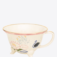 Ceramic cup with floral and swan design on a grey background