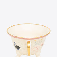 Decorative mug with gold rim and handle on a grey background
