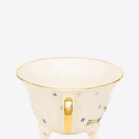 Ceramic footed cup with gold handle on a white background