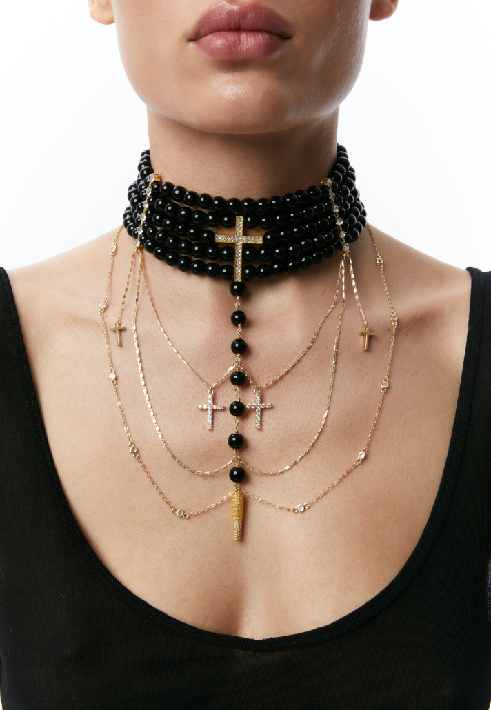 Close-up of a person wearing necklace with black beads and gold chains on a white background