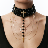 Close-up of a person wearing necklace with black beads and gold chains on a white background