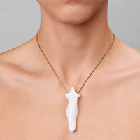 Person wearing a necklace with a white pendant on a neutral background